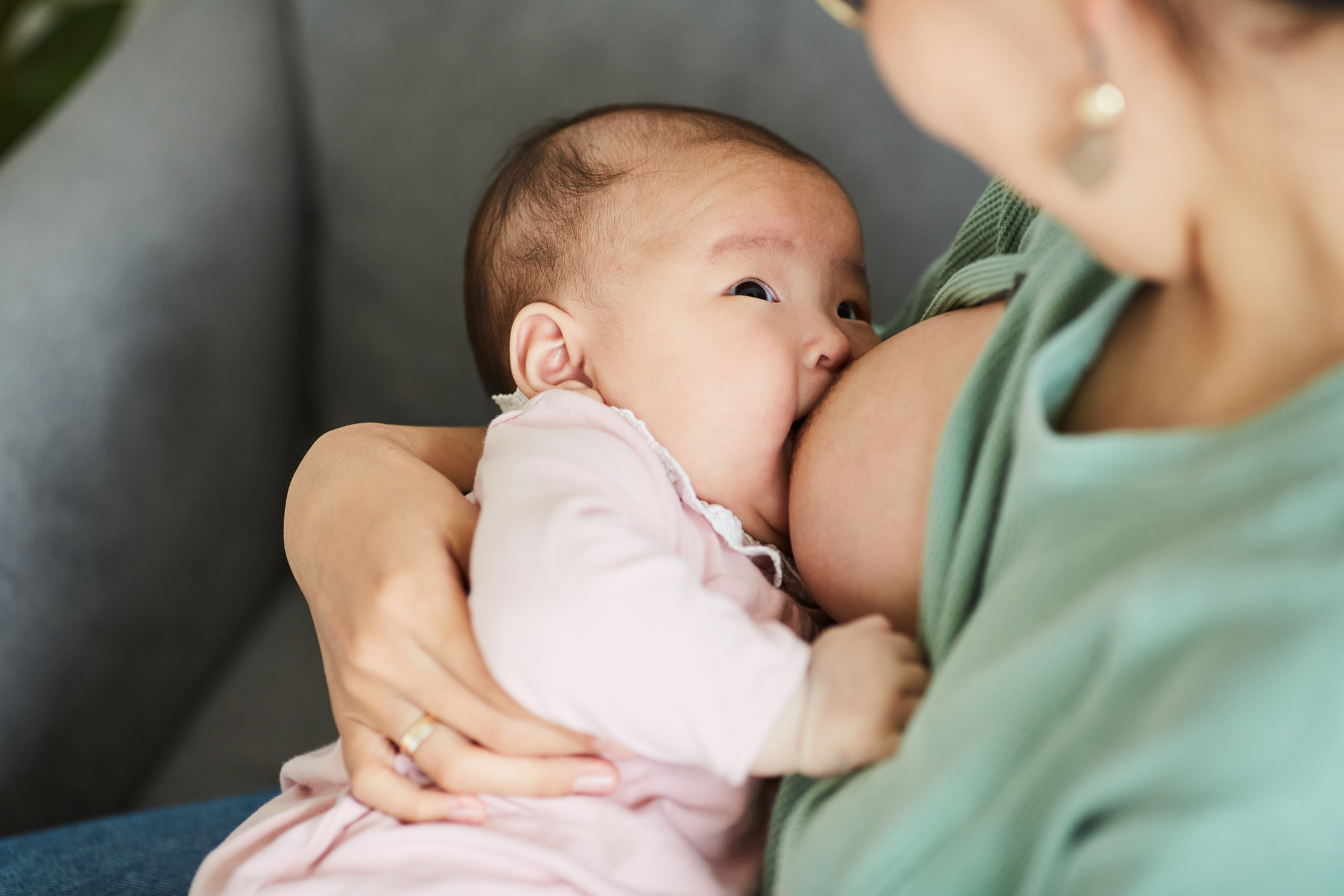 A baby being fed while holding her mother's hands