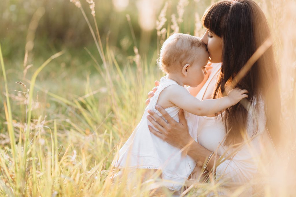 Mother and young daughter walking across a sunlit field